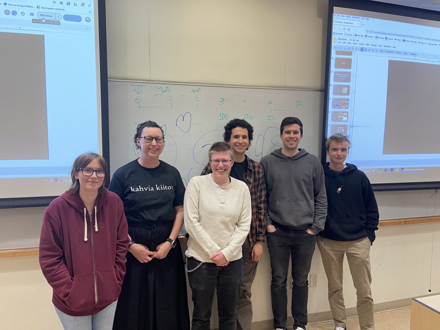 The club's new 6 officers in front of screens and a whiteboard